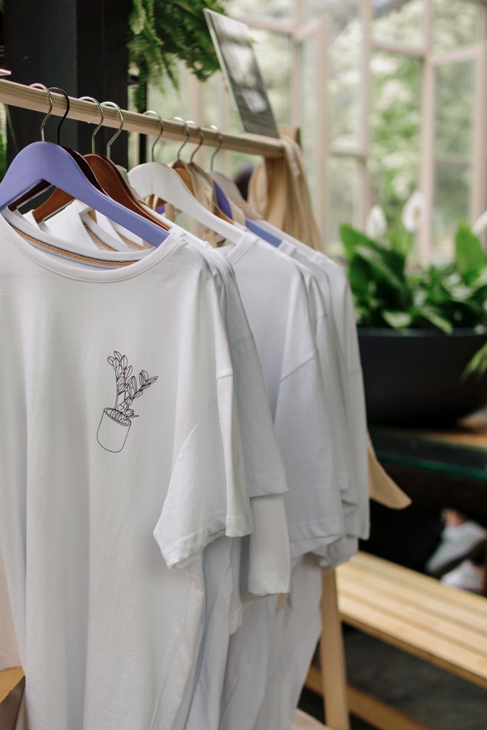 The Art of Drawing Readers In: Your attractive post title goes here Row of white t-shirts with plant design in a botanical-themed shop interior.